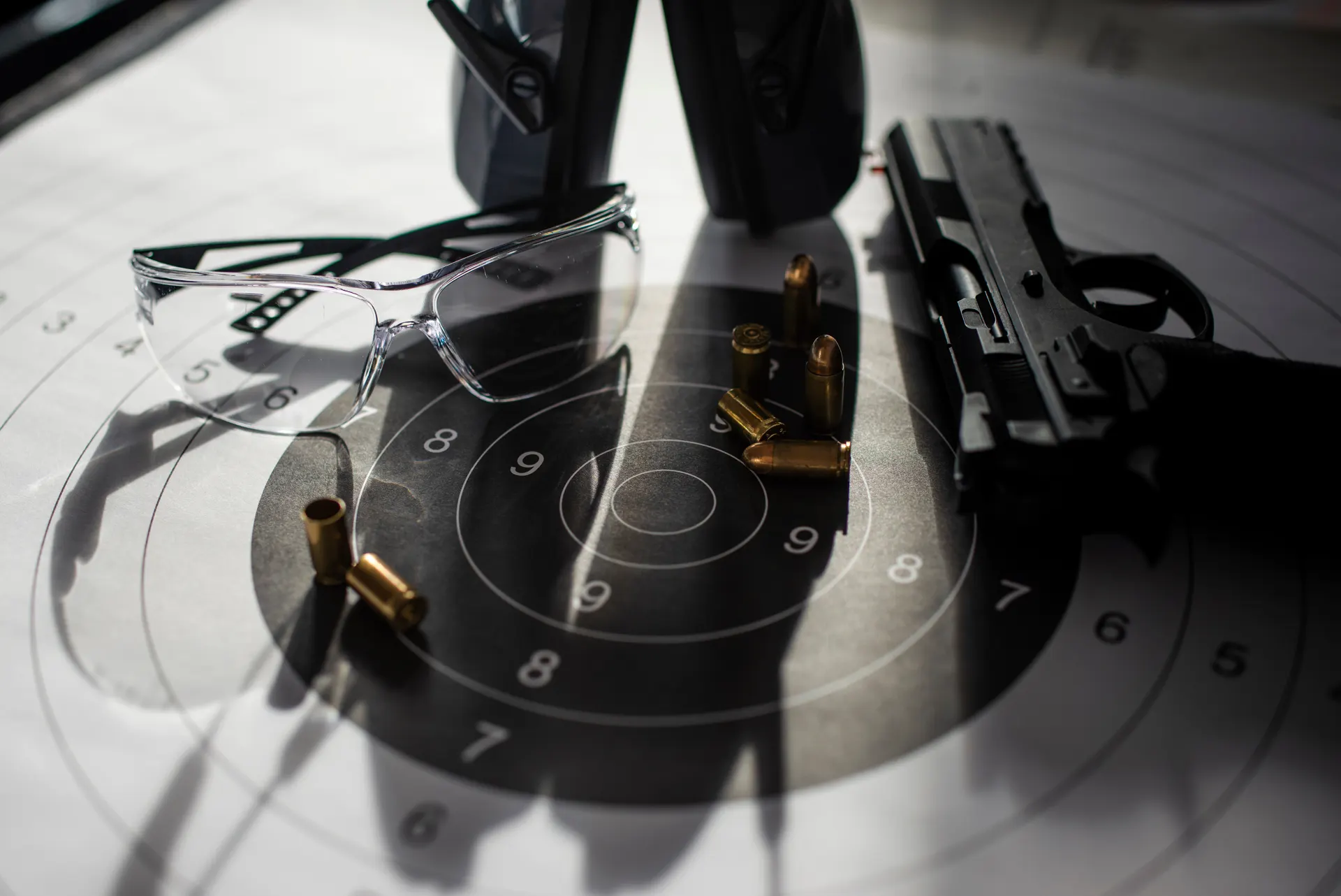 Pistole, Schutzbrille und Patronen auf einer Zielscheibe, Mitgliedschaft im Elite Shooting Club